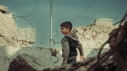 Child playing in destructed house of his family