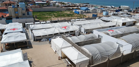 Aerial view of an ICRC field hospital with white tents near the coast, set up to provide emergency medical aid, in Rafah, Gaza.