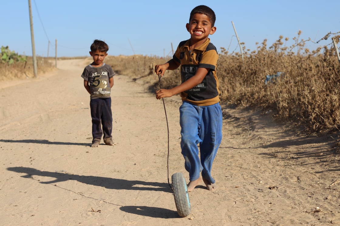 Raees, a deaf boy, plays with a wheel and a stick with his brother, in east of Jabalia, near the borders, where they reside in tents. ©ICRC, Gaza