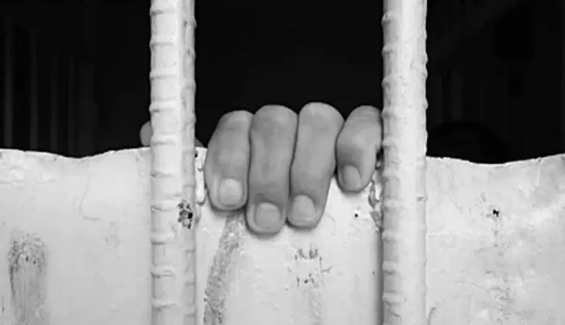 Image of fingers behind bars.